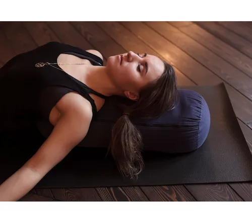 Une femme qui est relaxée pendant un cours de yoga restauratif