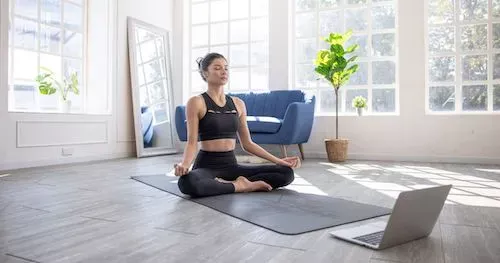 Une femme qui fait un cours de yoga en ligne depuis son ordinateur 
